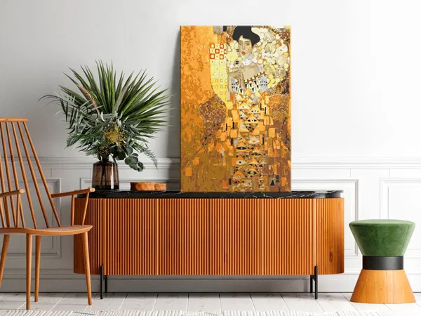 Contemporary living space with Gustav Klimt's 'Portrait of Adele Bloch-Bauer' displayed on a sideboard, surrounded by greenery and stylish furniture."