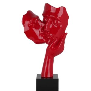 A striking glossy red modern sculpture depicting a stylized human face silhouette on a white display pillar.